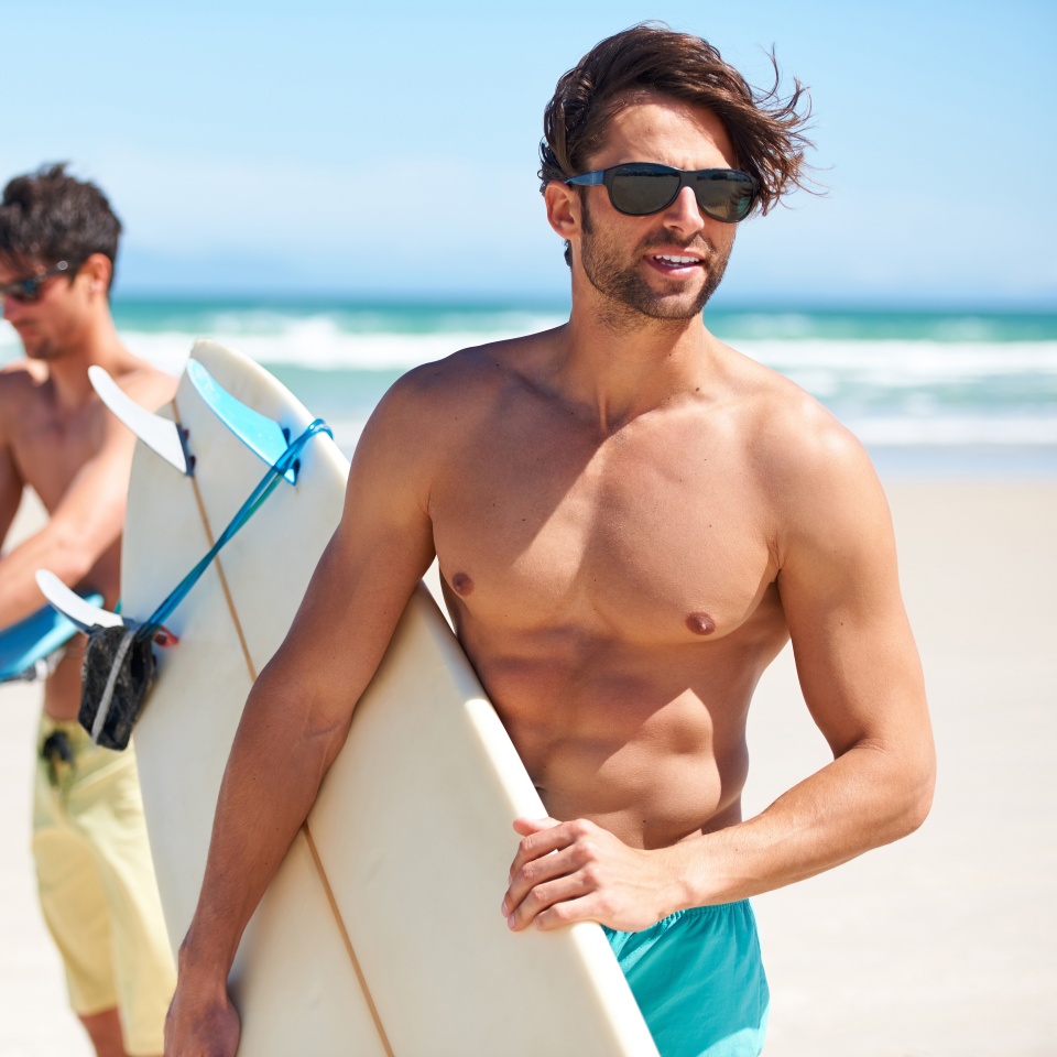 Surfs up. Two friends at the beach getting ready to head into the water for a surf.