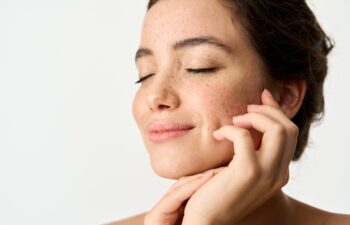 Aesthetic beauty photo of smiling young woman with freckles on face enjoying fresh clean healthy skin advertising skincare sunscreen cosmetics. Happy brunette Latin girl isolated on white background.